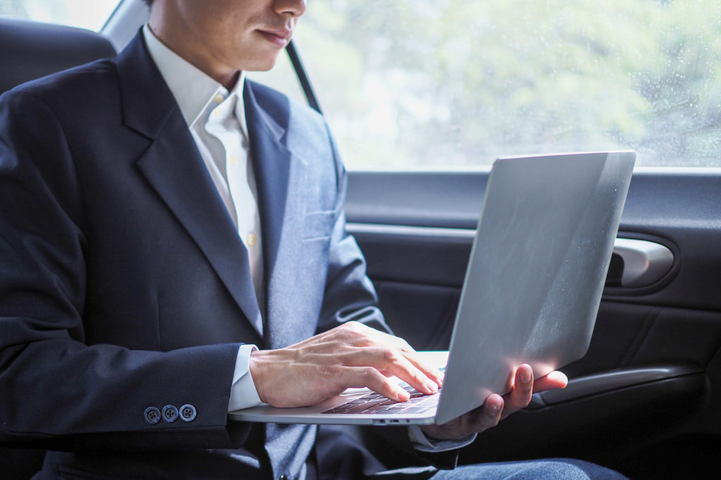 Car Service for Corporate Business Travel. Working on a laptop in a luxurious car.