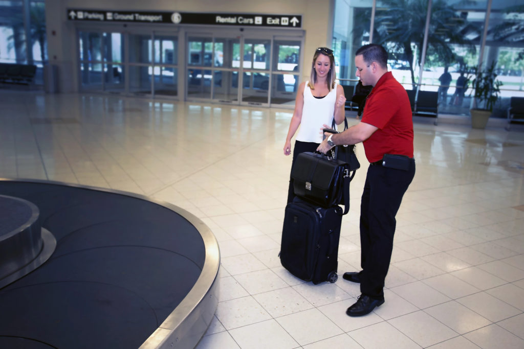 A driver taking a passengers luggage at the airport for them