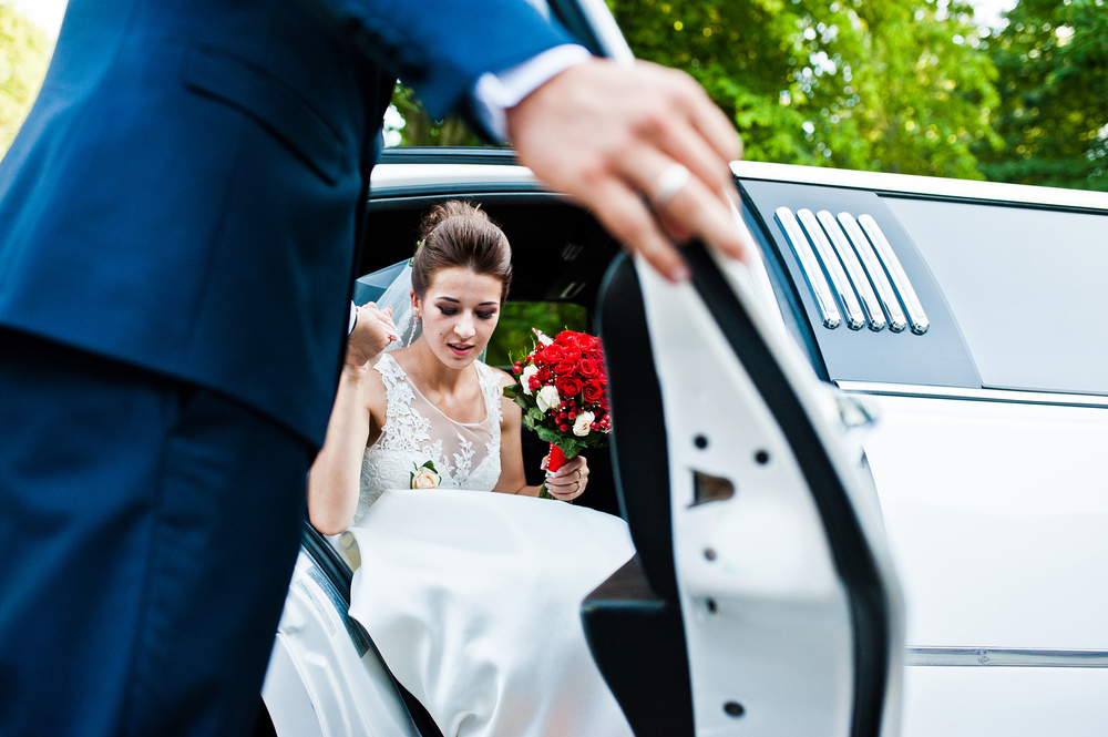 The groom opening the door of a limo for his bride
