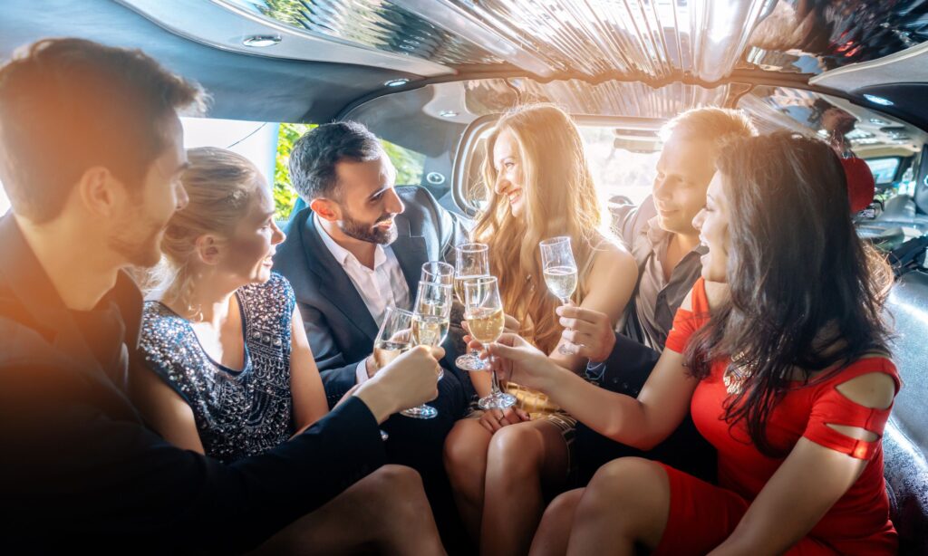 Group of well dressed people clinking wine glasses inside of a limousine.