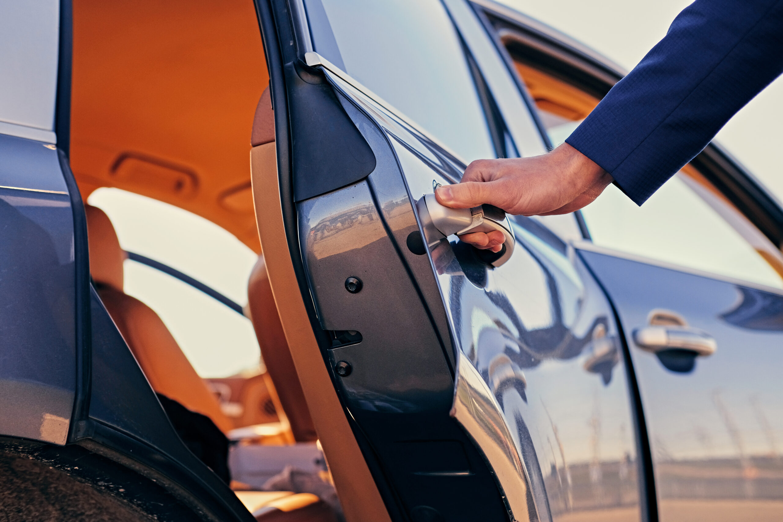 Chauffeur opening the door of a luxury private car service vehicle.